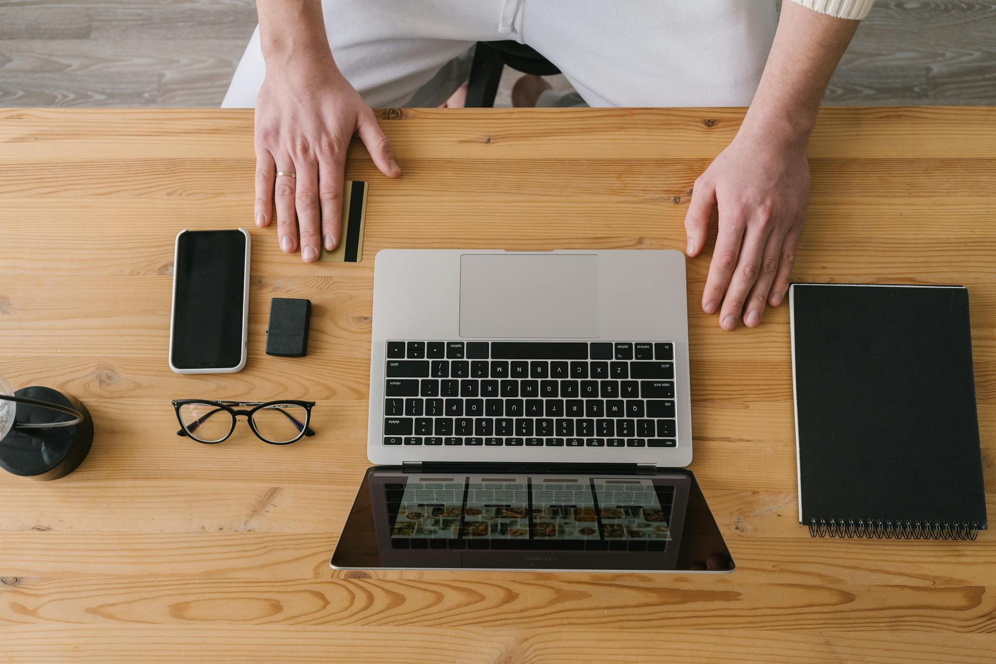 Hands on a laptop, surrounded by gadgets, on a wooden desk. Ideal for online shopping themes.